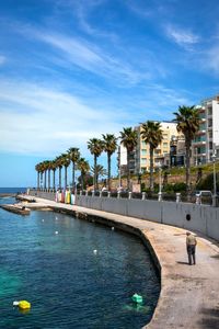 People swimming in pool by sea against sky