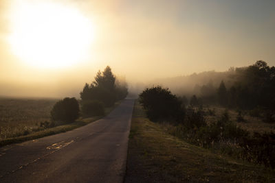 Road amidst trees against sky during sunset