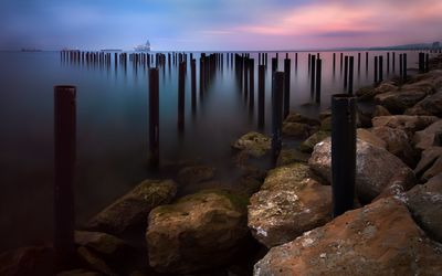 Wooden posts in lake against sky