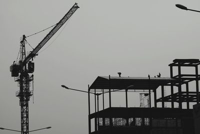 Low angle view of crane at construction site against clear sky