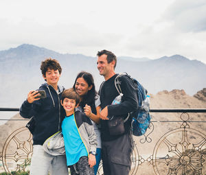 Portrait of friends standing on mountain against sky