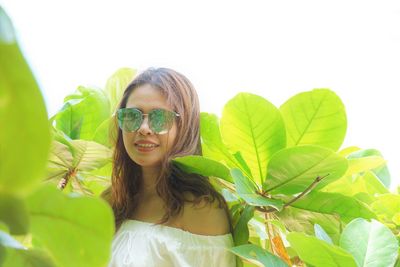 Portrait of woman wearing sunglasses standing by plants