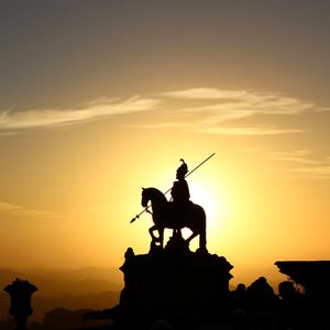 Silhouette statue against sky during sunset