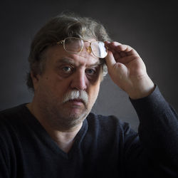 Close-up portrait of thoughtful man with eyeglasses against black background