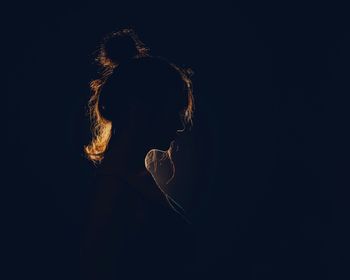 Side view of woman against black background