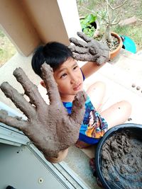 Portrait of boy showing muddy hands