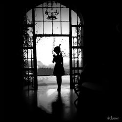 Silhouette of woman standing in glass window