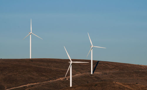 Wind turbines on the field against clear sky