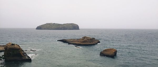 Rocks on sea against clear sky