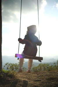 Low angle view of woman sitting on swing