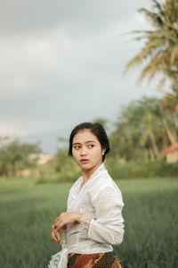 Thoughtful woman looking away while standing on field