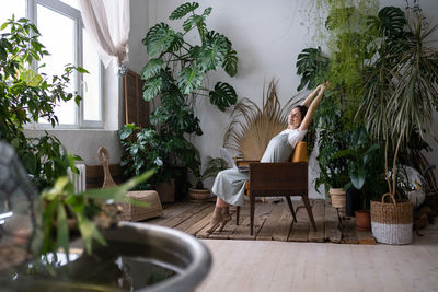 Beautiful student woman with hands behind head and laptop relaxing after e-learning in urban jungle.