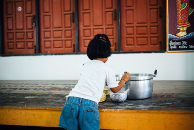 Rear view of girl with utensils on table at temple