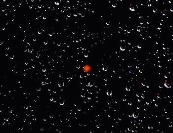 Full frame shot of raindrops on windshield against sky at night
