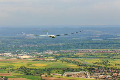 Aerial view of airplane flying over landscape against sky