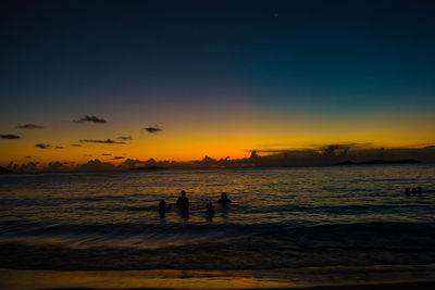 Silhouette people on beach against sky during sunset