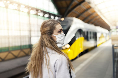 Young woman standing at railroad station