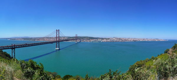 Suspension bridge over sea against blue sky