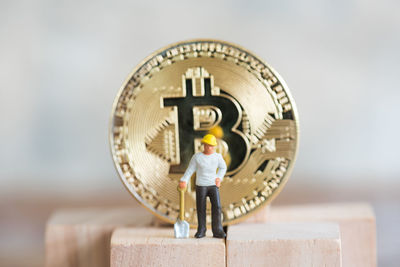 Close-up of male worker figurine with bitcoin on wood