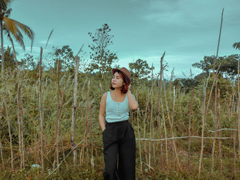 Portrait of young woman standing on field against sky