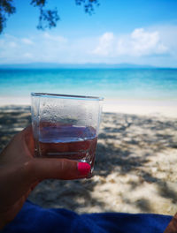 Hand holding glass of water at beach