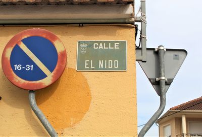 Low angle view of road sign against wall