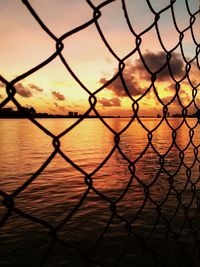 Full frame shot of chainlink fence against sky during sunset