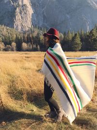 Side view of woman wrapped in shawl on grassy field