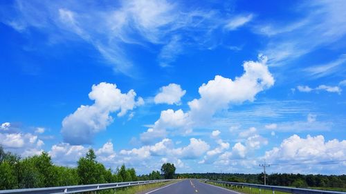 Road amidst trees against blue sky