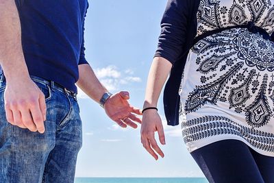 Midsection of couple standing against sky