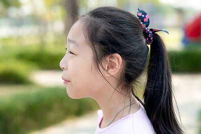 Close-up portrait of young woman looking away outdoors