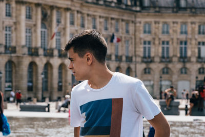 Teenage boy looking away while standing in city