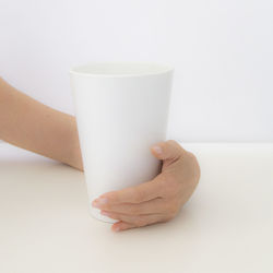 Close-up of hand holding drink against white background