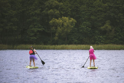 Rear view of woman with umbrella on lake against trees