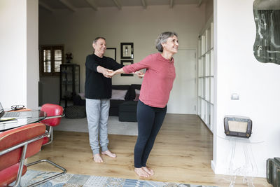 Senior man assisting woman in doing yoga