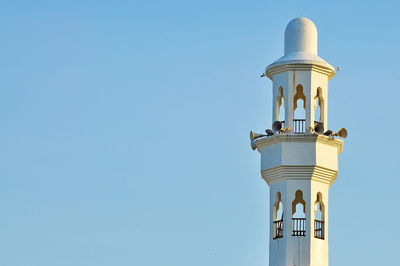 Low angle view of megaphones on minaret against clear blue sky