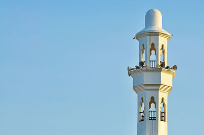 Low angle view of lighthouse against clear blue sky