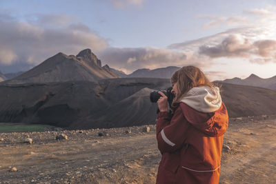 Young woman taking photographs of mountains in highlands of iceland