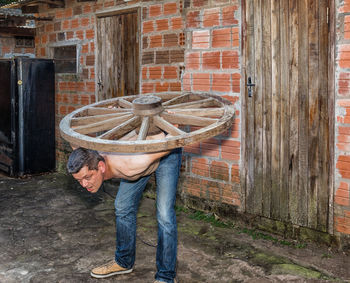 Man working on wood against brick wall