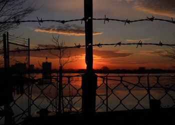 Silhouette of barbed wire fence at sunset