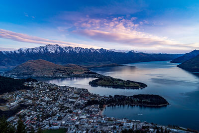 Aerial view of lake by snowcapped mountains against sky during sunset