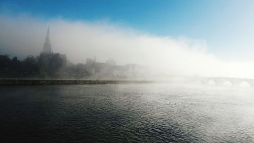 View of city by river against sky