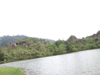 Scenic view of river by mountains against clear sky