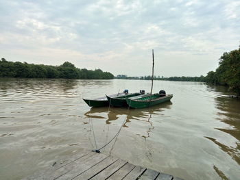 Boat moored on lake against sky