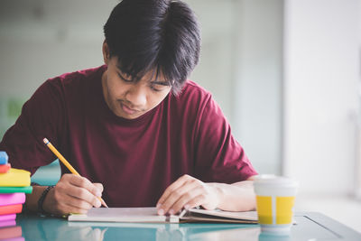 Man writing at table in cafeteria