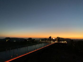 Illuminated city against sky at sunset