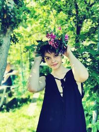 Portrait of beautiful young woman standing by flowering plants