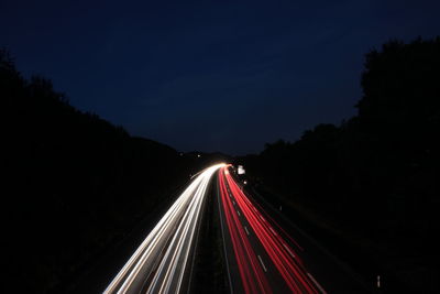 Light trails on road against sky at night