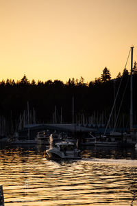 Sailboats on lake against clear sky during sunset