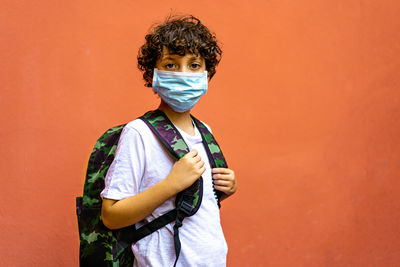 Portrait of teenage girl standing against orange wall